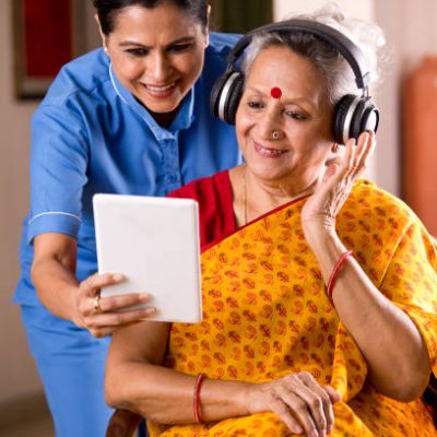 Female nurse with senior women having fun watching media content on digital tablet at home